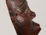 an image of a wooden mask on a stand against a white background