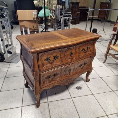 une petite commode dans une pièce où il y a beaucoup de meubles
