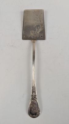 une cuillère en argent avec un manche sur une surface blanche