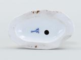 a white porcelain object with a blue flower on it
