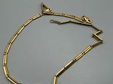 gros plan d'un bracelet en or sur une surface grise