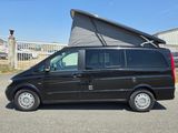 une camionnette noire garée sur un parking, avec une tente posée sur le toit