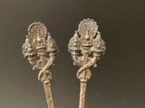 pair of antique silver spoons with handles and handles on a table