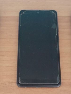 un téléphone portable cassé posé sur une table à côté d'une souris d'ordinateur
