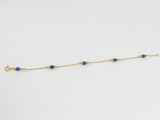 un bracelet en chaîne dorée orné de perles de lapis-lazuli sur fond blanc