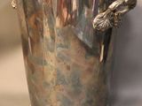 a silver vase with a bird on it on a table