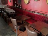 tables and chairs in a restaurant with red walls and a clock on the wall