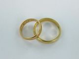 two gold wedding rings on a white surface