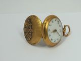 a gold pocket watch with a white face on it