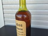 an old bottle of liquor sitting on top of a black table