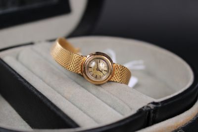 une montre en or posée dans un écrin sur une surface blanche
