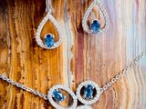 a close up of a necklace and earrings on a wooden surface