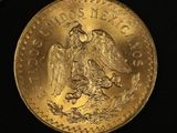 a close up of two gold mexican coins on a black surface