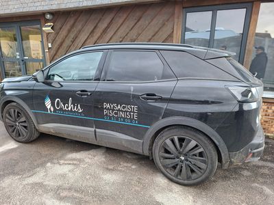 une voiture noire garée devant un immeuble sur lequel est accrochée une pancarte