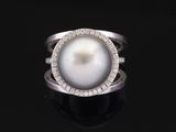 une bague en perles blanches et diamants sur une surface noire