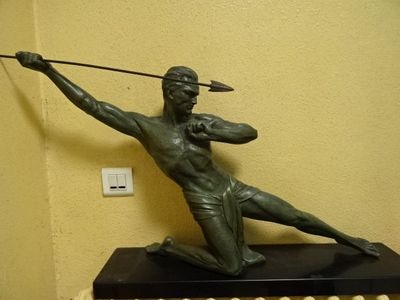 statue d'un homme tenant une lance et un arc, posée sur une table