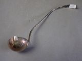 a silver spoon with a handle on a gray surface