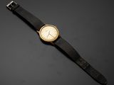 une montre dorée et noire posée sur une surface noire