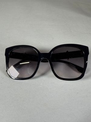 des lunettes de soleil « œil de chat » noires posées sur une surface blanche