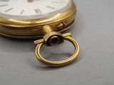 un gros plan d'une montre de poche en or sur laquelle est fixé un anneau