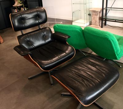 un fauteuil en cuir noir et un pouf vert dans un salon