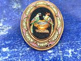 une photo d'une broche sur laquelle figure un oiseau