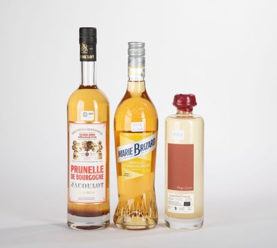trois bouteilles d'alcool et une bouteille de vin posées sur une surface blanche