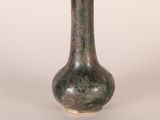 a green vase that is sitting on a white surface
