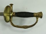 a gold sword with a black handle on a white surface