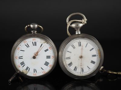 une paire de montres de poche anciennes, avec des chiffres romains se détachant sur un fond noir