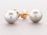 pair of pearl and gold stud earrings on a white surface