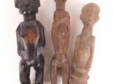 trois figurines en bois assises les unes à côté des autres sur une surface blanche