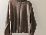 the sweater is hanging on a hanger on the wall
