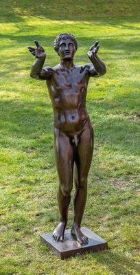 statue of a man holding a peace sign in a grassy field