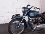a blue motorcycle parked in front of a white brick wall