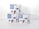 trois cartons de vin posés sur une table, à côté d'un verre de vin
