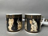 pair of black and gold coffee mugs with figures on them