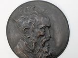 un vieux médaillon en bronze sur lequel est représenté le visage d'un homme