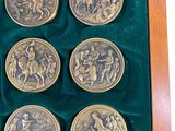 four gold coins in a wooden box with velvet lining