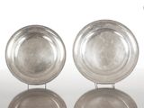 paire de plats en argent plaqué posés sur un support, sur un fond blanc avec reflet