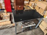 a black table with a glass top in a warehouse