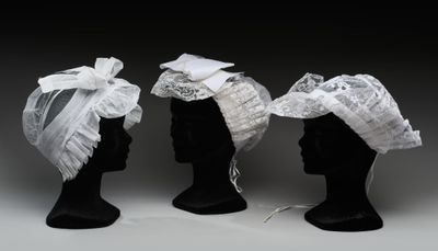 trois têtes de mannequins noires ornées de dentelle blanche et de nœuds
