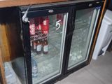 un réfrigérateur avec une porte vitrée dans lequel se trouvent des boissons
