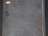 an old, rusted piece of metal hanging on a black wall