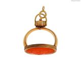 une image représentant un pendentif doré et rouge muni d'un anneau