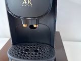 a black coffee maker on a wooden stand on a white surface