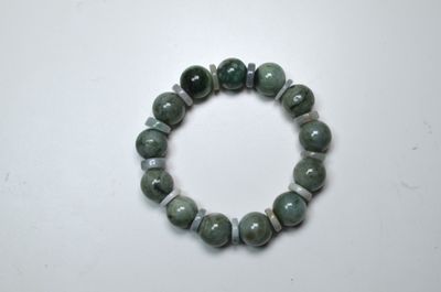 un bracelet composé de perles de jade vert sur un fond blanc