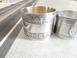two silver cups sitting on a table with a striped tablecloth
