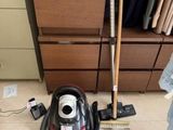 un aspirateur posé par terre à côté d'un balai
