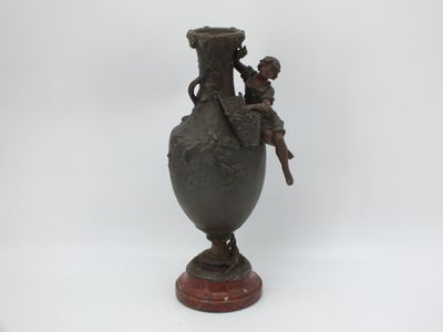 un vase en bronze sur lequel sont assis un garçon et une fille